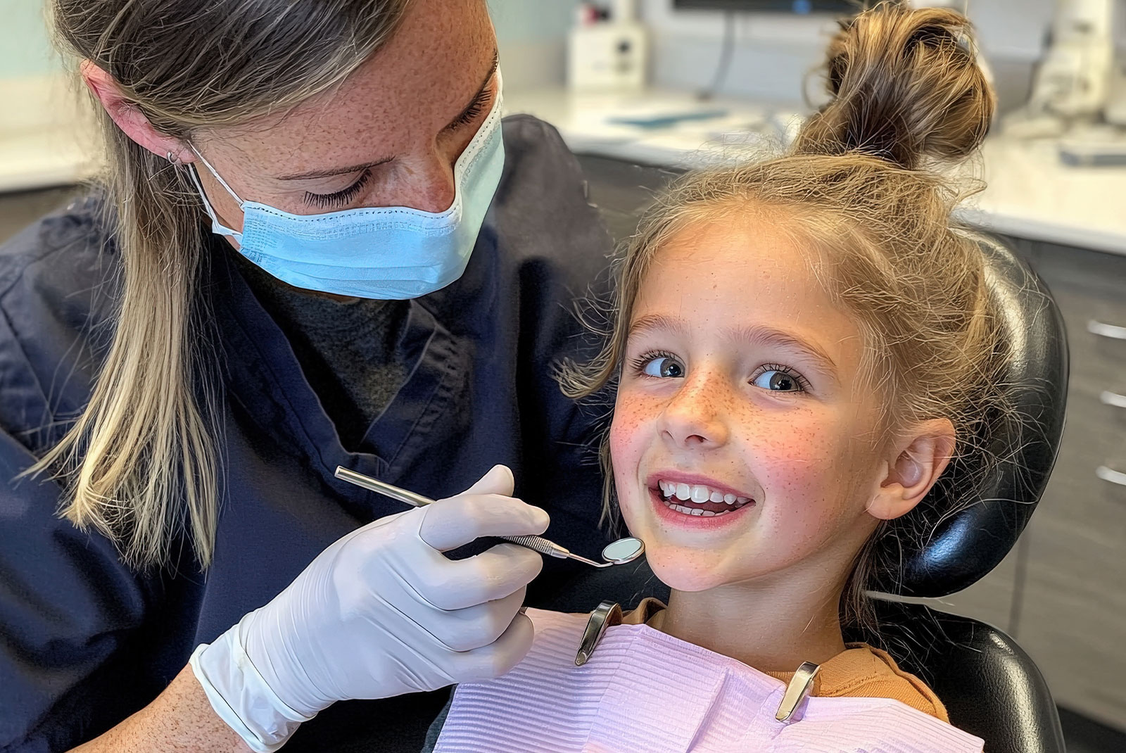 child being examined for their dental procedure by staff member