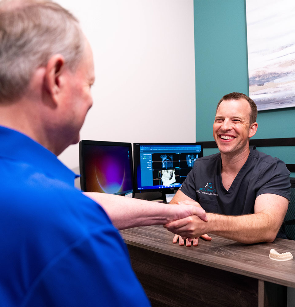 patient and doctor smiling brightly and shaking hands during consultation