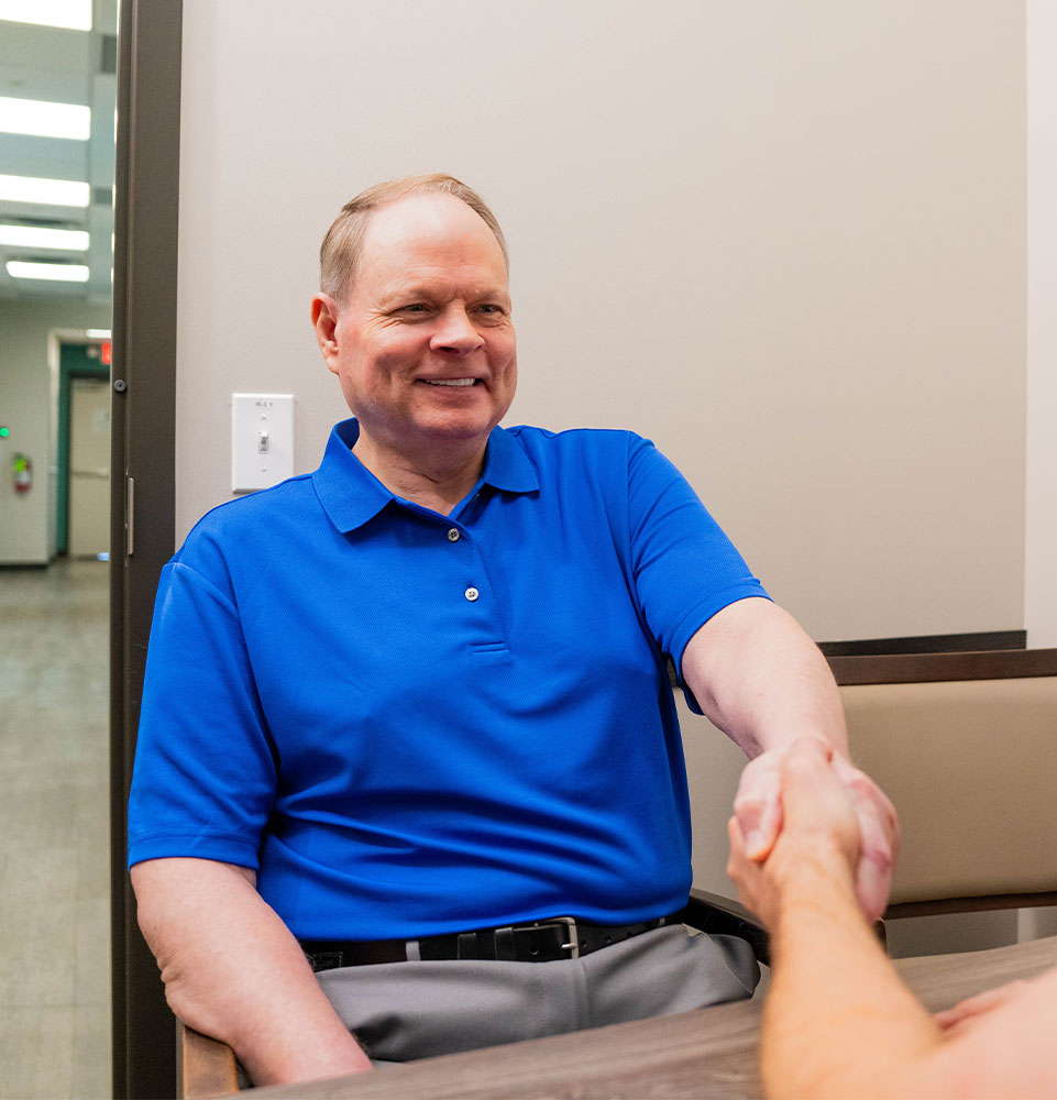 patient smiling and shaking hands with doctor for their consultation