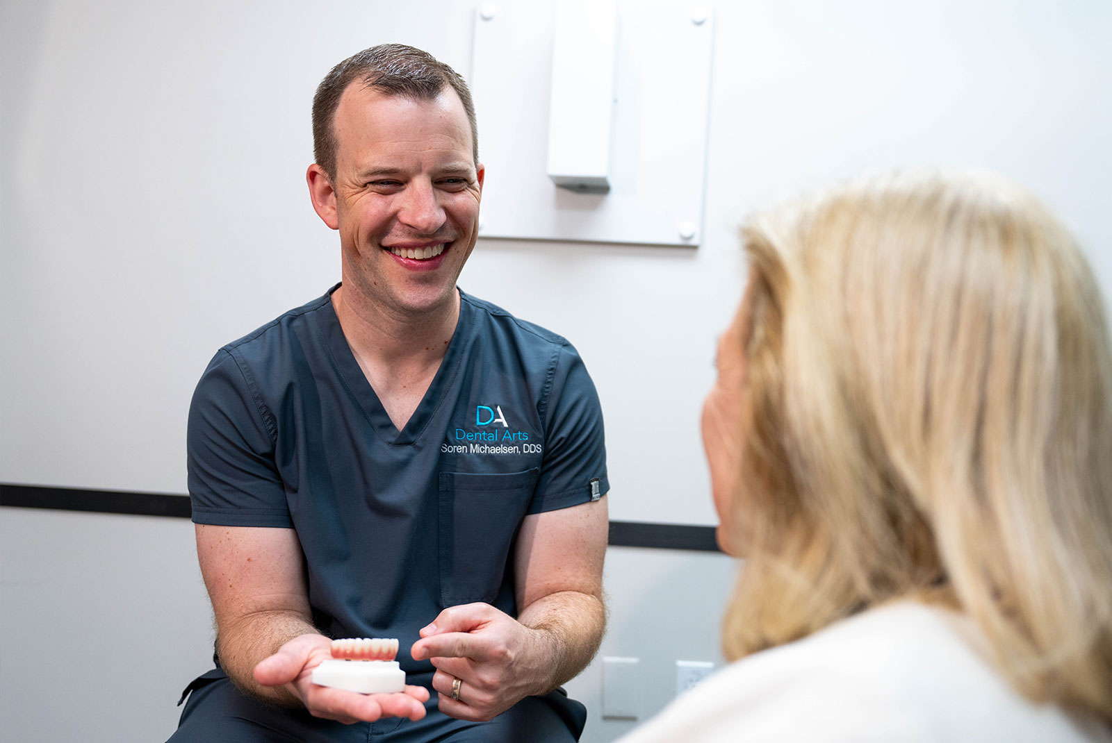 doctor smiling brightly while going over dental procedure information with patient