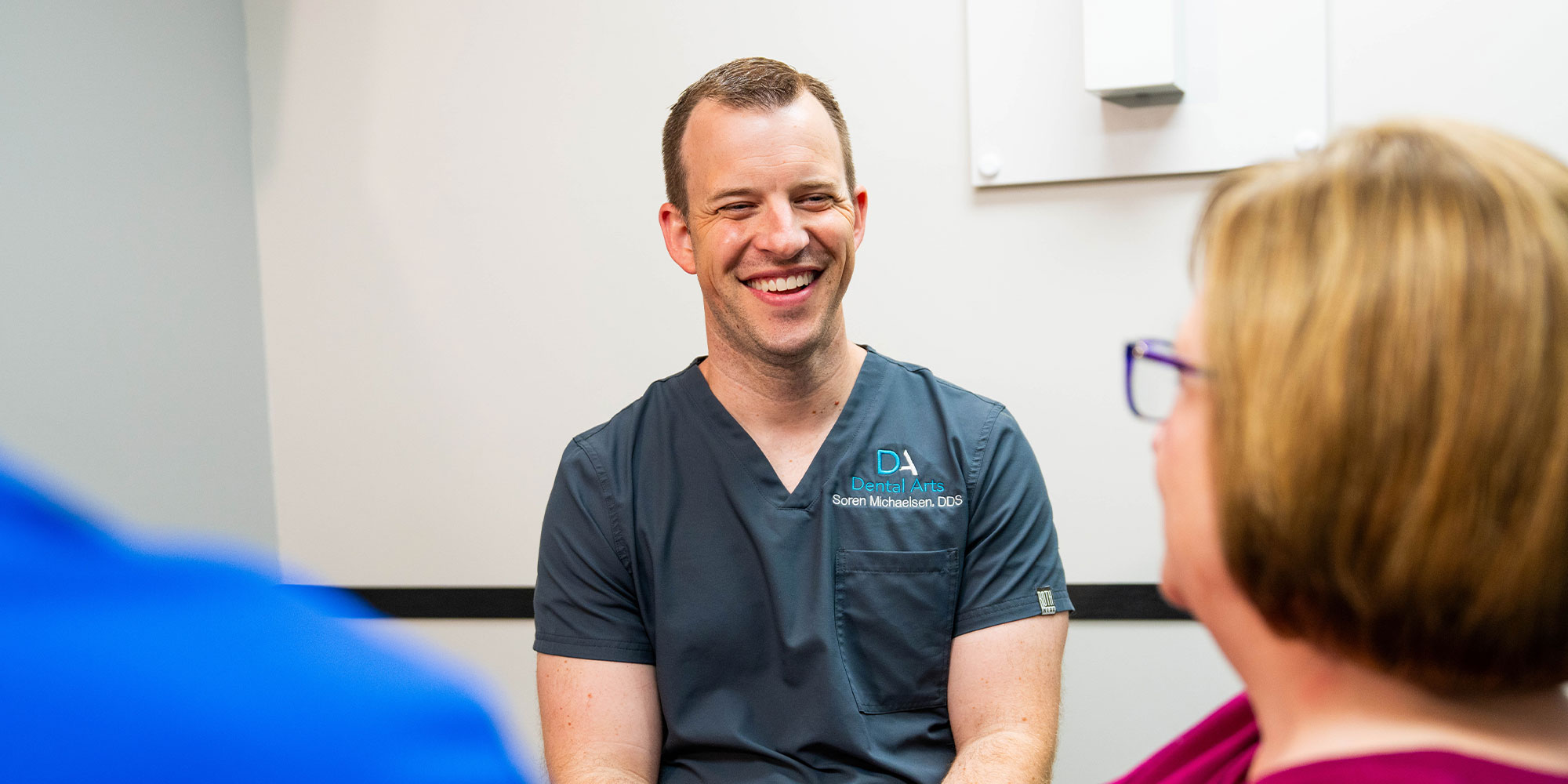 doctor smiling brightly while going over dental procedure information with patient