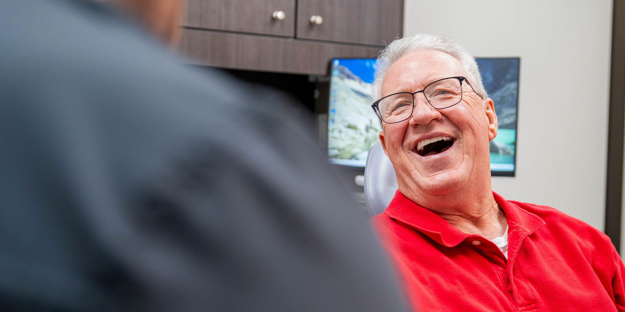 patient smiling brightly while going over dental procedure information with doctor