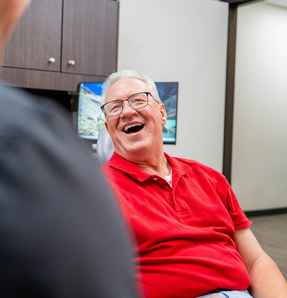 patient smiling brightly while going over dental procedure information with doctor