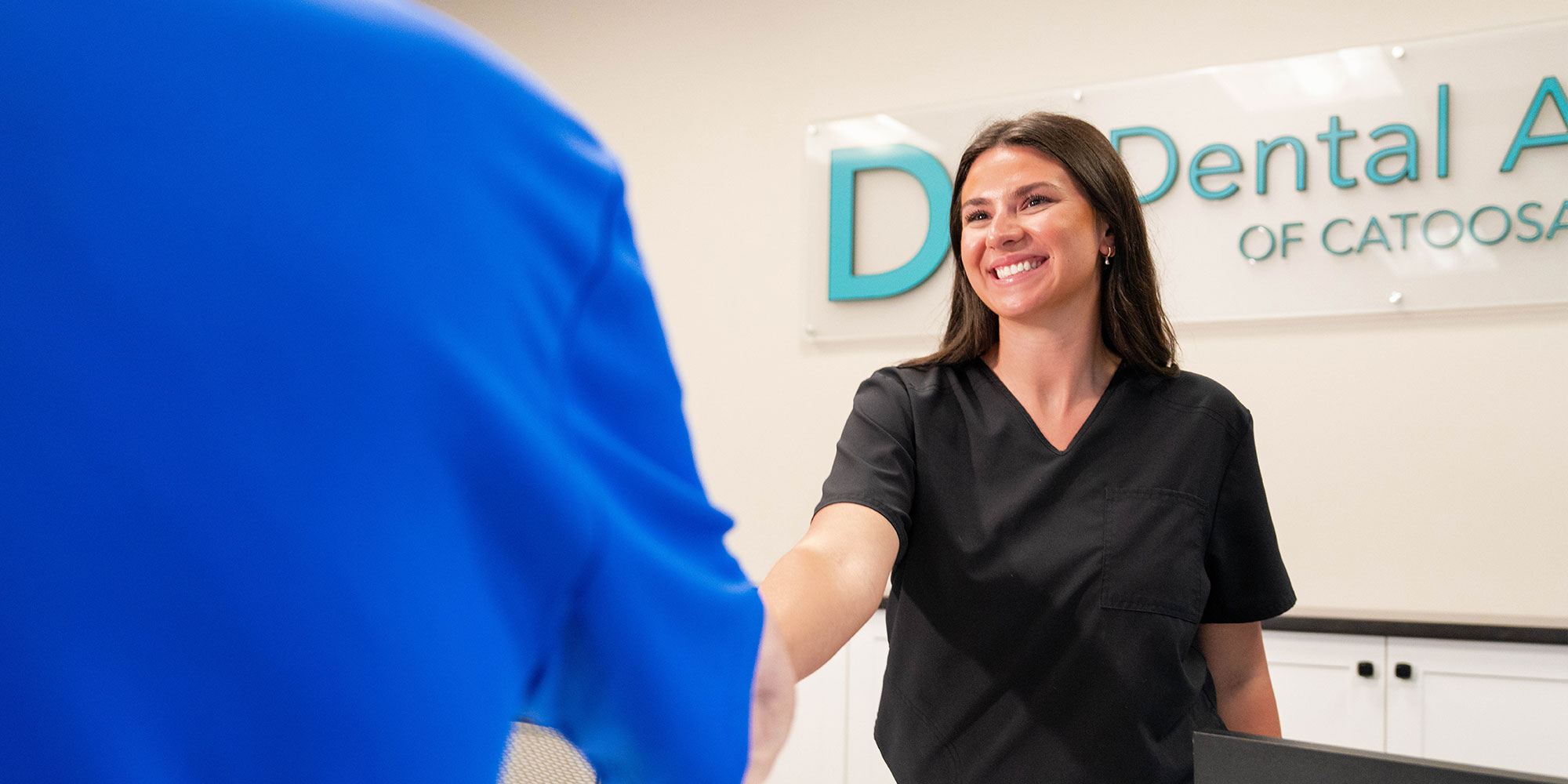 staff member shaking hands with greeting dental patient within the dental center