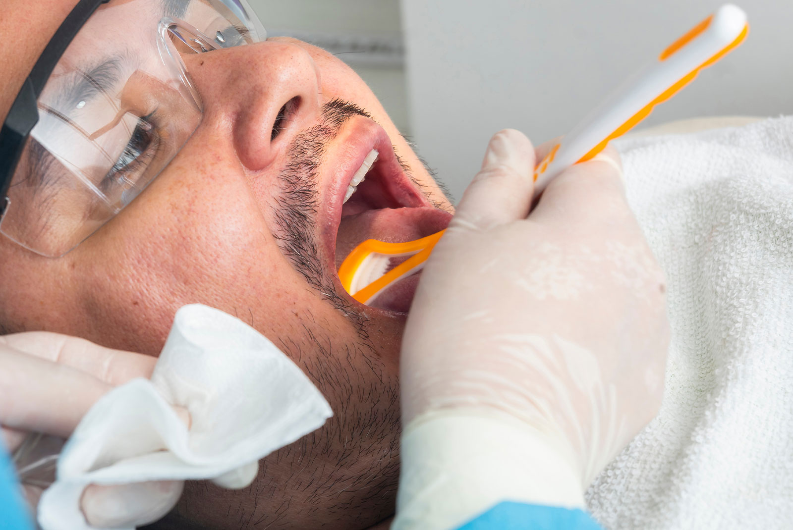 Close-up of a dental professional cleaning a patient’s tongue with a tongue scraper during an oral hygiene session.