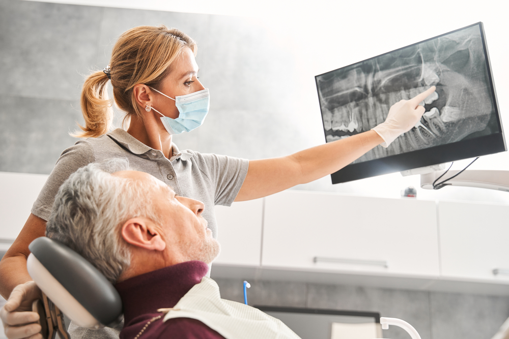 dentist showing a older patient his xray of teeth emergency